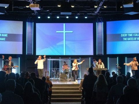 A church worship service with the band on stage and lyrics on the screens