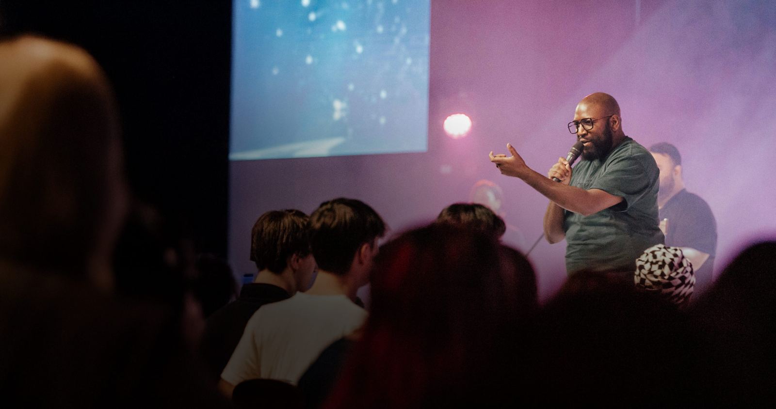A pastor speaking to a church gathering under stage lights